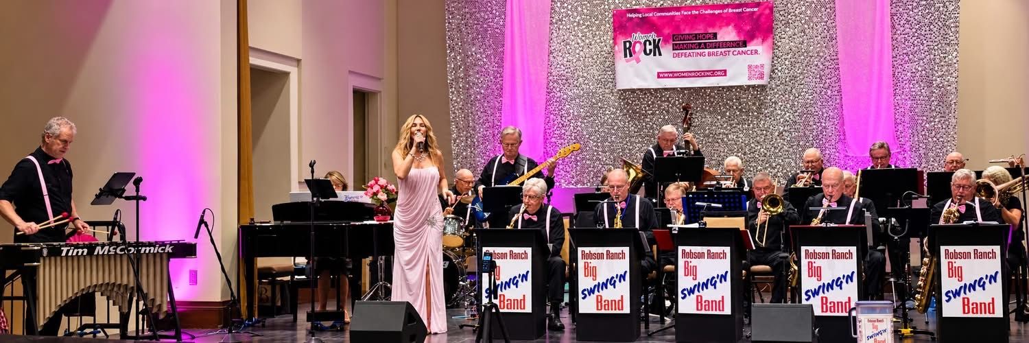 The Robson Ranch Big Swing'n Band performing on stage at the Pink Fling under pink lights, with a vocalist in a pink gown at center and Tim McCormick playing vibraphone at far left