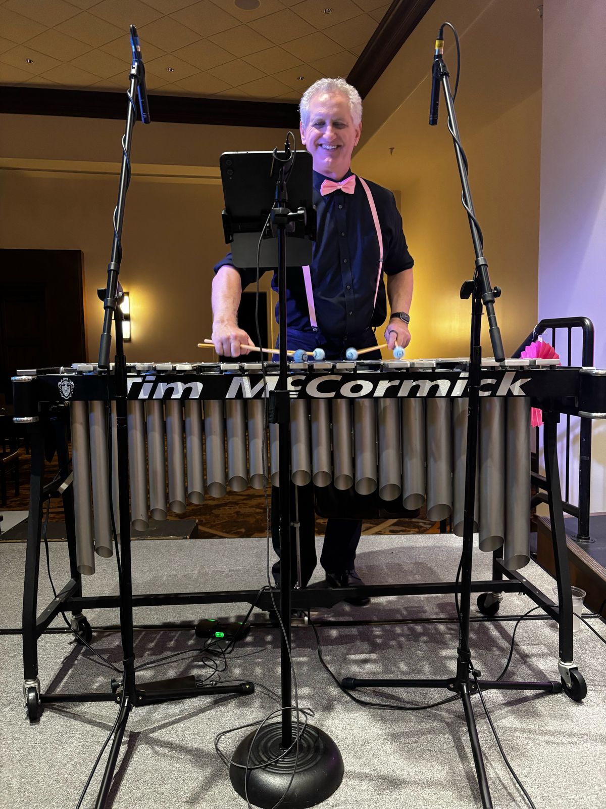 Tim McCormick smiling as he plays the vibraphone, in a pink bow tie and pink suspenders, at the Pink Fling